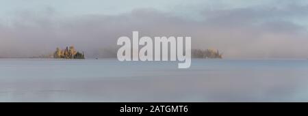 A lake in the forest in Canada, during the Indian summer, with fog on the water in the morning Stock Photo