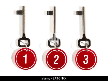 Three matching keys with red numbers on circular key tags on rings arranged in a row on white with shadow Stock Photo