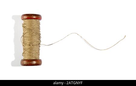 Wooden vintage reel of twine on white with a length of the thread unravelled and copy space Stock Photo