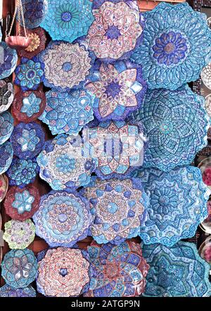 Traditional Iranian souvenirs - copper plates and dishes with floral persian ornament on enamel, Grand bazaar of Isfahan, Iran Stock Photo