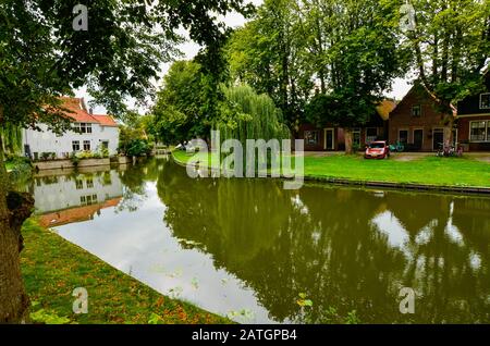 Edam, Netherlands, August 2019. One of the pretty canals of this city: the foliage of the trees is reflected on the water along the banks, pretty hous Stock Photo