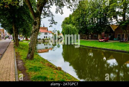 Edam, Netherlands, August 2019. One of the pretty canals of this city: the foliage of the trees is reflected on the water along the banks, pretty hous Stock Photo