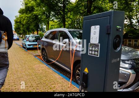 Edam, the Netherlands, August 2019. An Mitsubishi electric car parked and connected to the charging station. The orange cable connected to the car is Stock Photo