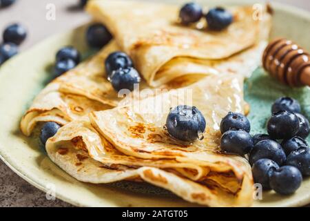Thin sweet crepe pancakes with blueberries and honey. Stock Photo