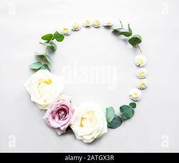 Decorative circle frame with pink and white roses and leaves on white background. Flat lay Stock Photo