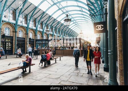 London, UK - May 15, 2019: People enjoying in Covent Garden Market, view with sunflare. Located in the West End of London, Covent Garden is renowned f