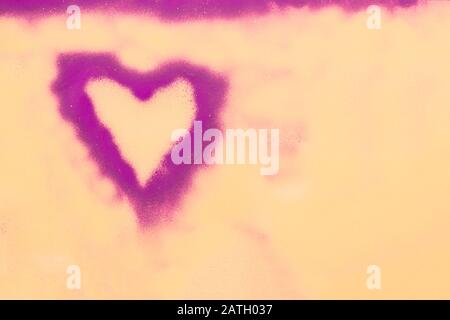 Painted pink heart made of spray paint on a yellow wall. Valentines day concept. Stock Photo