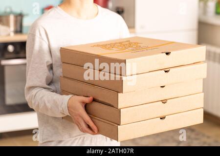 home food delivery. girl holds order for pizza or pies on blurred background in home. Stock Photo