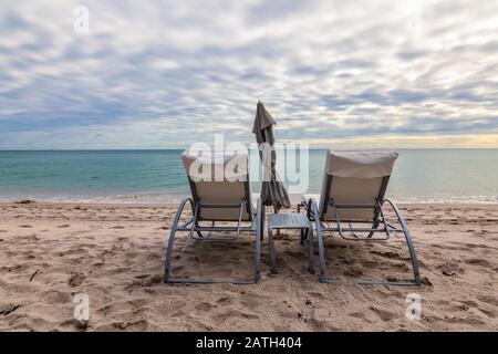 Two empty beach chairs on the beach in Hollywood on a cloudy day, Florida. Stock Photo