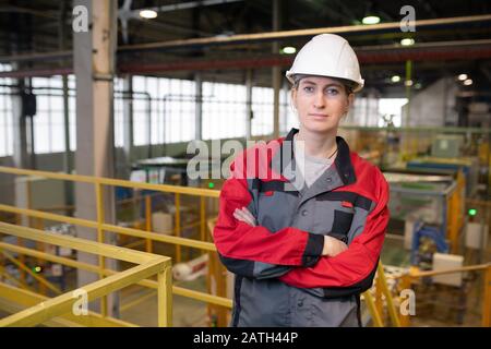 Portrait of serious confident female factory worker in hardhat crossing arms on chest Stock Photo