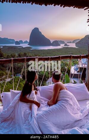 Phangnga Bay Thailand, couple in bed waking up in the jungle of Phangnga Bay looking out over the ocean and Island of the bach during suinrise Stock Photo