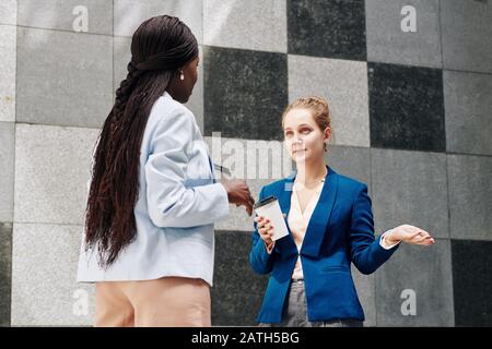 Businesswomen drinking take away coffee during break and discussing new project Stock Photo