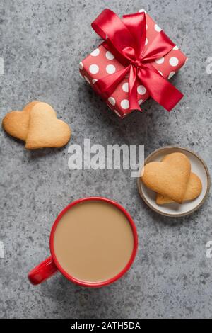 Valentines day greeting card with gift, homemade heart cookies and coffee cup on grey stone table. Top view. Vertical format. Stock Photo