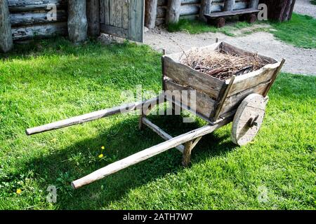 Vintage cart with brushwood in front of old wooden house. Stock Photo