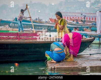 Varanasi, India - Nov 12, 2015. Three Indian Hindu women, wearing traditional saris, pray and light candles beside the Ganges River, during Diwali. Stock Photo
