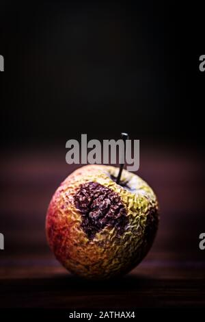 Withered and dried up apple on wooden table, old and foul fruit, copyspace Stock Photo