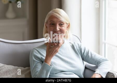 Middle-aged woman talk on cellphone using loudspeaker Stock Photo