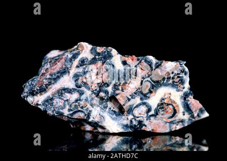 Raw rhodonite with manganese mineral stone in front of black background, mineralogy and esotericism Stock Photo