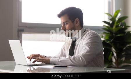 Businessman seated at desk launching online startup project using laptop Stock Photo