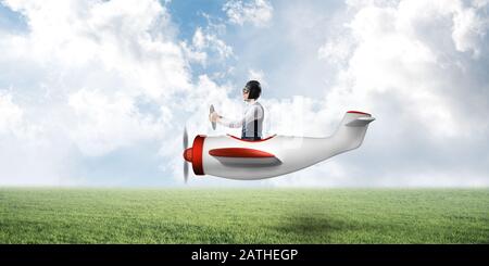 Man in airplane flying low above green meadow Stock Photo