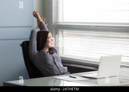 Businesswoman leaned on chair at workplace finished work feels satisfied Stock Photo