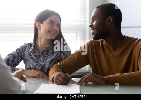 Interracial couple closing deal buy first property signing agreement Stock Photo
