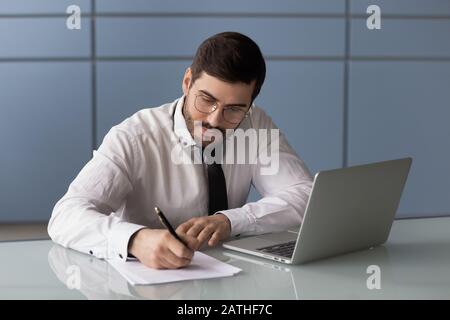 Businessman signs documents do paperwork seated at workplace Stock Photo