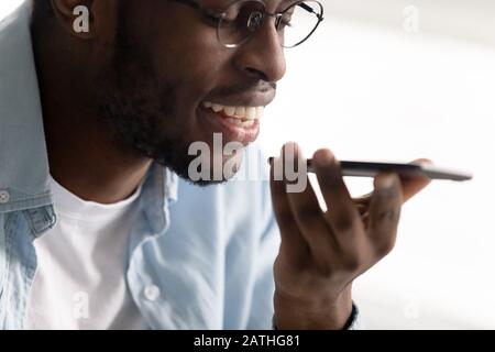 African guy holding smartphone using virtual digital voice assistant Stock Photo