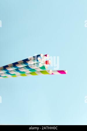 Retro style striped multi-colour paper straws on a blue background Stock Photo