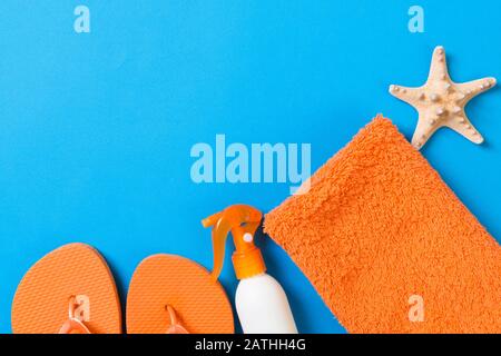 Top view of Beach flat lay accessories. sunscreen bottle with seashells, starfish, towel and flip-flop on Colored background with copy space. Stock Photo