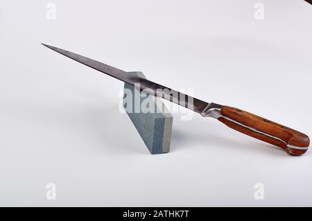 old used cook knife, on a stone for sharpening, white background Stock Photo