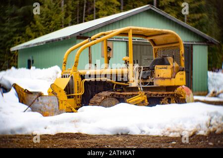 A Caterpillar D2 bulldozer crawler with an attached snow plow blade, in the snow, on Eagle View, in Noxon, Montana Stock Photo