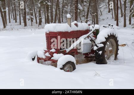 An old 1957 International Farmall 350 tractor in the snow on a farm in Valley of the Moon, Rock Creek, Montana. Stock Photo