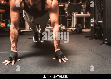 A bearded sporty man in the gym is doing yoga exercises, practicing standing in the plank pose, doing push up or push up exercises. Stock Photo