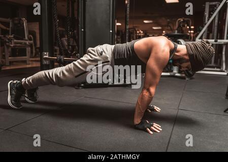 A bearded sporty man in the gym is doing yoga exercises, practicing standing in the plank pose, doing push up or push up exercises. Stock Photo