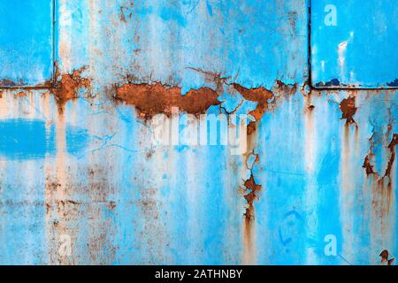 Blue paint peeling off the rusty metal surface, grunge shabby textures and background Stock Photo