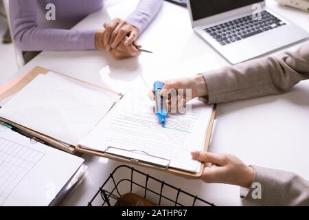Close-up of unrecognizable consultant highlighting text in contract for customer while explaining key point Stock Photo