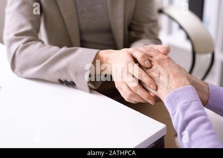 Close-up of unrecognizable social worker holding hands of elderly woman while supporting her Stock Photo