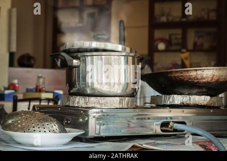 A boiling pot on a gas stove in an outdoor dining room on the street. Thai and Asian street food. cooking soup. Stock Photo