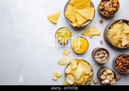Veraity bowls of beer snacks and sauces on stone table. Nuts, chips, nachos, crackers. Top view with copyspace Stock Photo