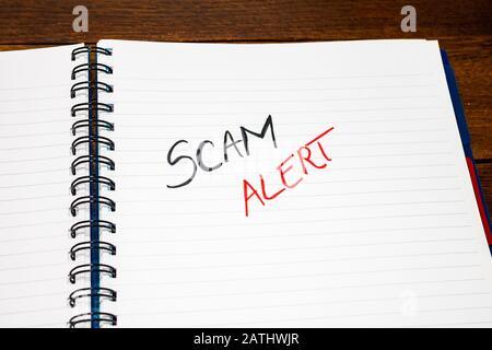 Scam alert handwriting  text on paper, on office agenda. Copy space. Stock Photo