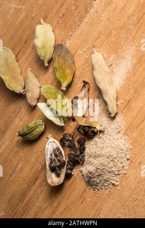 Green cardamom pods, seeds and ground spice. Close-up on natural wooden background Stock Photo