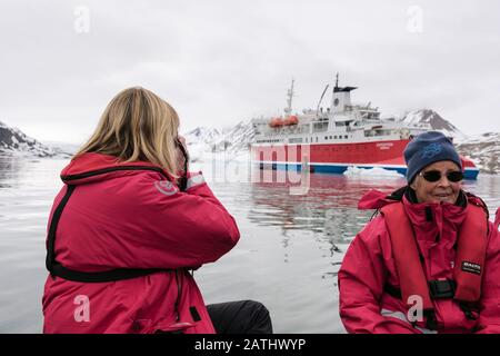 Two female passengers wearing life jackets on a boat off from G Adventures Expedition cruise ship. Spitsbergen island, Svalbard, Norway, Scandinavia Stock Photo