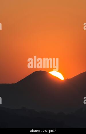 The sun sets behind Whimble Hill on the border between England and Wales, near Knighton, Powys, UK Stock Photo