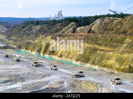 Big yellow mining trucks working in the limestone open-pit. Loading and transportation of minerals in the chalk open-pit. Belarus, Krasnoselsk, in the Stock Photo