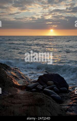 Westward Ho! seascape sunset with waves crashing around the rocks Stock Photo