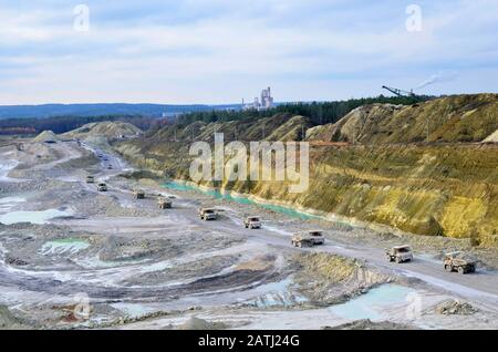 Big yellow mining trucks working in the limestone open-pit. Loading and transportation of minerals in the chalk open-pit. Belarus, Krasnoselsk, in the Stock Photo