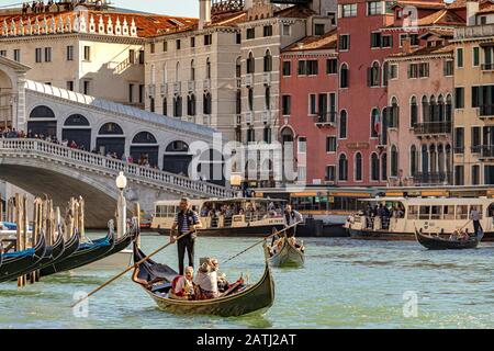 A Gondolier steering his Gondola carrying tourists along The Grand Canal near The Rialto Bridge ,Venice,Italy Stock Photo