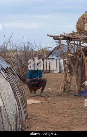 Omorate, Ethiopia - Nov 2018: Dasanech tribe man sitting on the mini chair. Omo valley Stock Photo