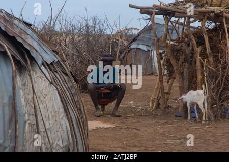 Omorate, Ethiopia - Nov 2018: Dasanech tribe man sitting on the mini chair. Omo valley Stock Photo